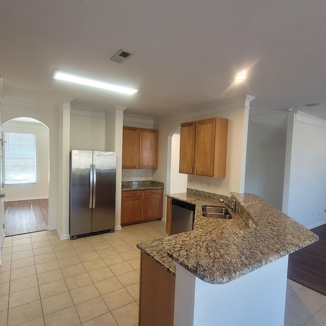 kitchen with a peninsula, a sink, visible vents, appliances with stainless steel finishes, and crown molding