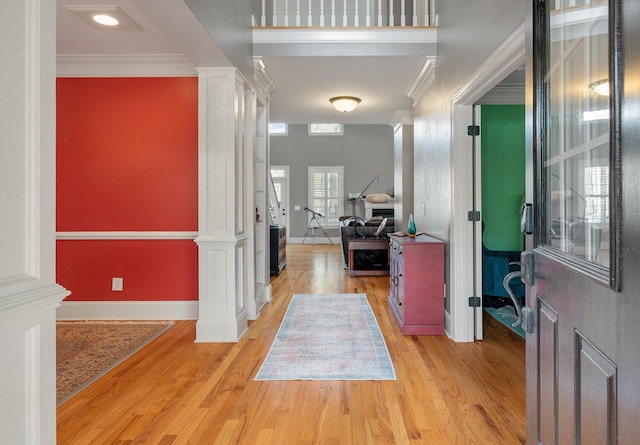 entrance foyer featuring light wood-type flooring, ornate columns, and crown molding