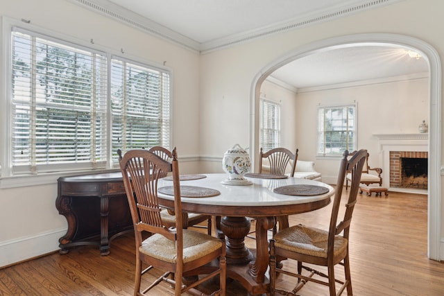 dining room with arched walkways, light wood finished floors, and plenty of natural light