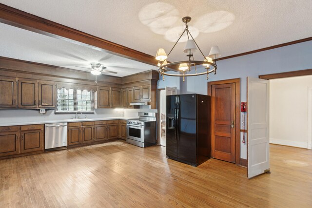 kitchen featuring a textured ceiling, stainless steel appliances, light countertops, light wood finished floors, and decorative light fixtures