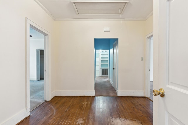 hallway with dark wood finished floors, visible vents, crown molding, and baseboards