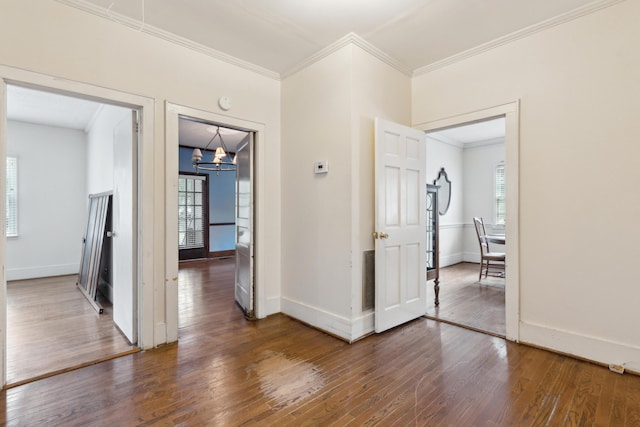 hall with dark wood-style floors, ornamental molding, baseboards, and an inviting chandelier