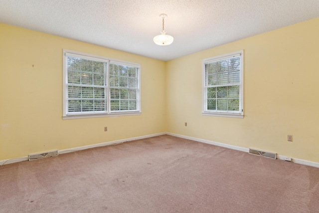 unfurnished room featuring carpet floors, visible vents, and a healthy amount of sunlight