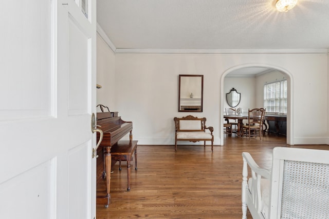 entryway featuring crown molding, arched walkways, dark wood finished floors, and a textured ceiling