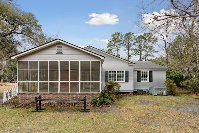 rear view of property with cooling unit, a sunroom, and a lawn