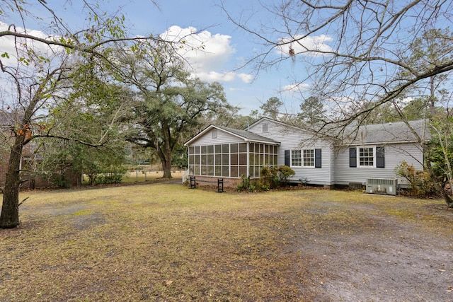 back of house featuring a yard, a sunroom, and central air condition unit