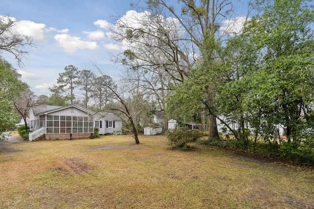 view of yard featuring an outbuilding, a sunroom, and a shed