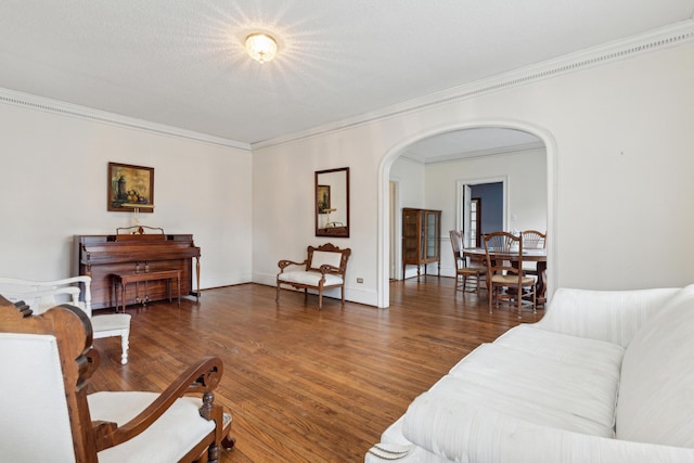 living room with arched walkways, baseboards, dark wood-style floors, crown molding, and a textured ceiling