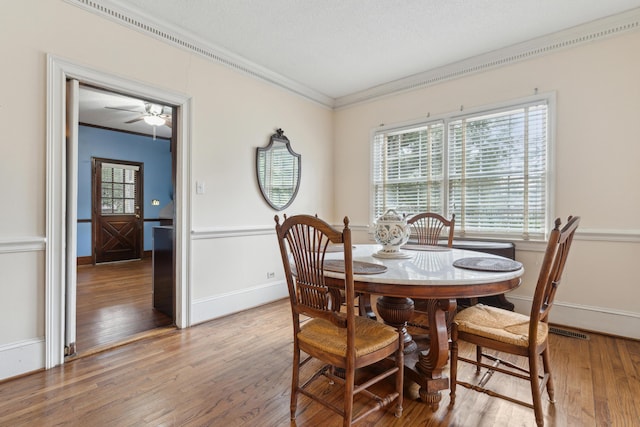 dining area featuring baseboards, a textured ceiling, ornamental molding, and hardwood / wood-style floors