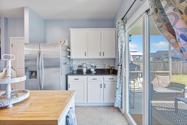 kitchen featuring decorative backsplash, a healthy amount of sunlight, stainless steel fridge with ice dispenser, and white cabinetry