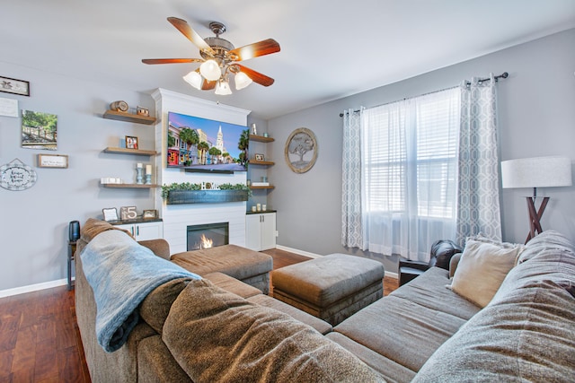 living room featuring ceiling fan, a fireplace, dark wood finished floors, and baseboards