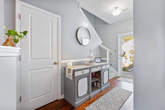 foyer entrance featuring dark wood-style floors, stairs, and visible vents