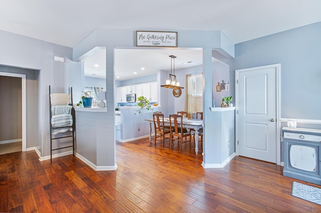 kitchen with a chandelier, dark wood-style flooring, white cabinetry, baseboards, and stainless steel microwave