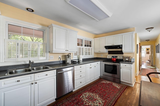 1067 Loyalist Ln, Mount Pleasant, SC 29464 - kitchen with stainless steel appliances, under cabinet range hood, dark countertops, white cabinetry, and wood finished floors