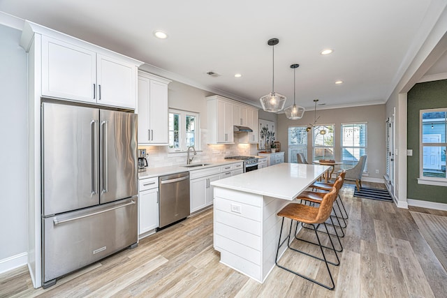 kitchen featuring appliances with stainless steel finishes, a center island, white cabinets, and decorative light fixtures