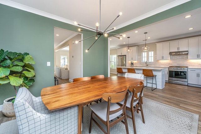 dining room featuring crown molding, sink, and light hardwood / wood-style floors