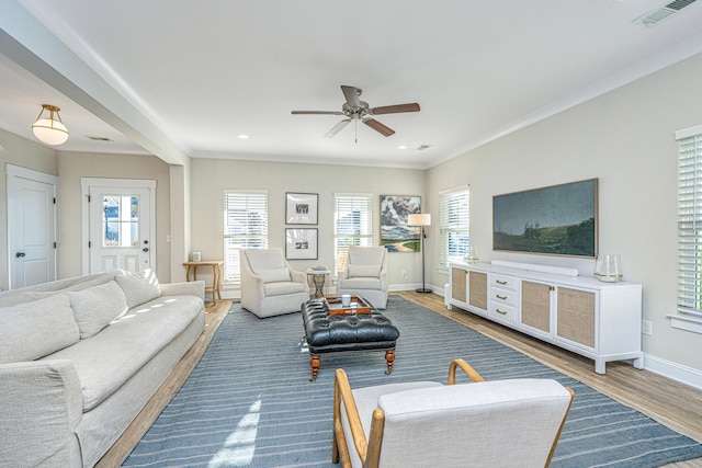 living room featuring ceiling fan, hardwood / wood-style flooring, ornamental molding, and a healthy amount of sunlight