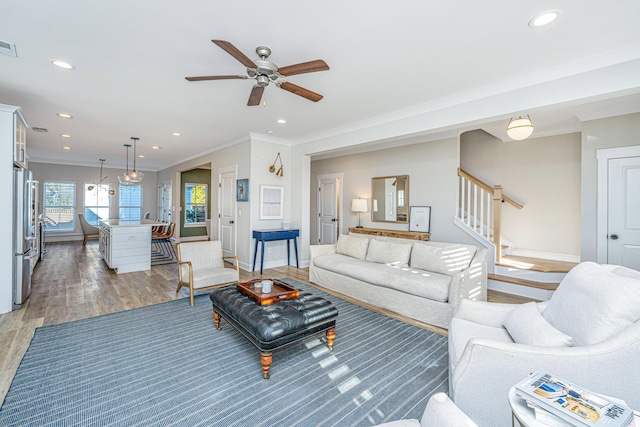 living room with hardwood / wood-style floors, crown molding, and ceiling fan