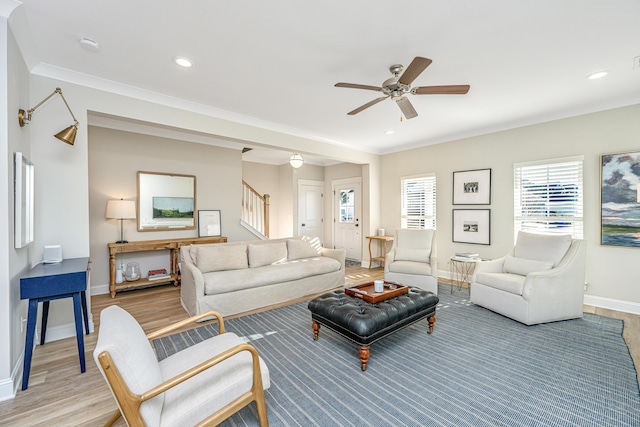 living room with ceiling fan, ornamental molding, and light hardwood / wood-style floors