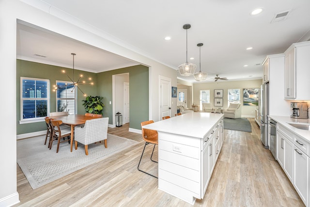 kitchen featuring a breakfast bar, white cabinetry, decorative light fixtures, a kitchen island, and stainless steel appliances