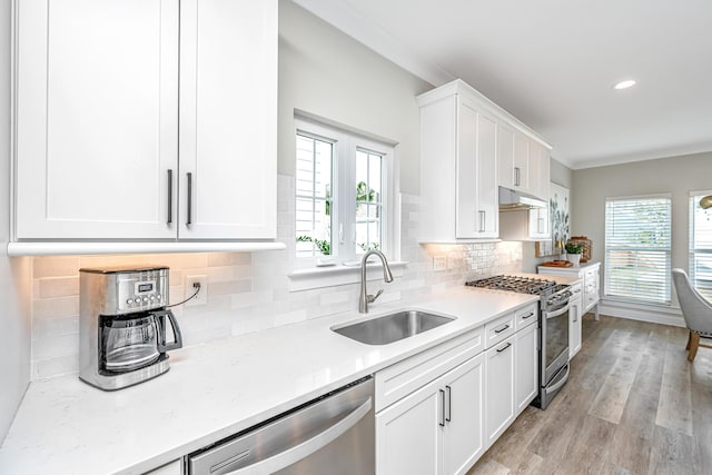 kitchen featuring sink, stainless steel appliances, white cabinets, decorative backsplash, and light wood-type flooring