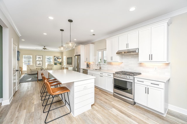 kitchen with sink, appliances with stainless steel finishes, backsplash, white cabinets, and decorative light fixtures