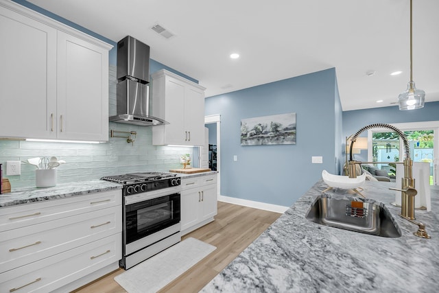 331 Saddlewood Dr, Charleston, SC 29414 - kitchen with range with gas stovetop, wall chimney range hood, decorative backsplash, light wood-style floors, and white cabinets