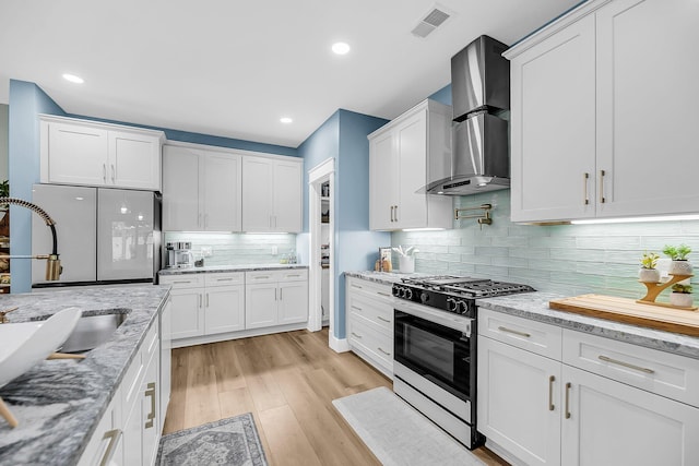 331 Saddlewood Dr, Charleston, SC 29414 - kitchen with gas range, wall chimney exhaust hood, freestanding refrigerator, white cabinets, and light wood finished floors