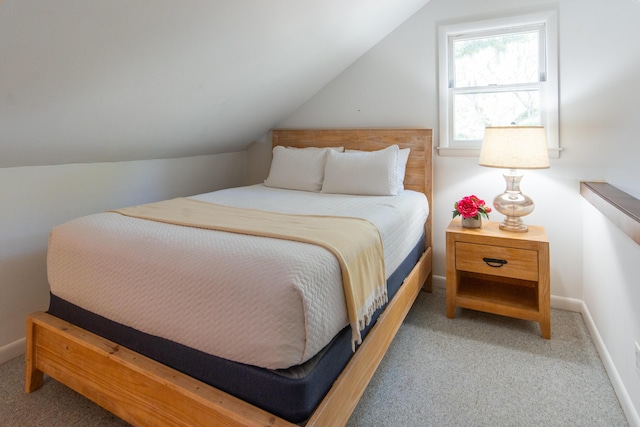 carpeted bedroom featuring lofted ceiling and baseboards