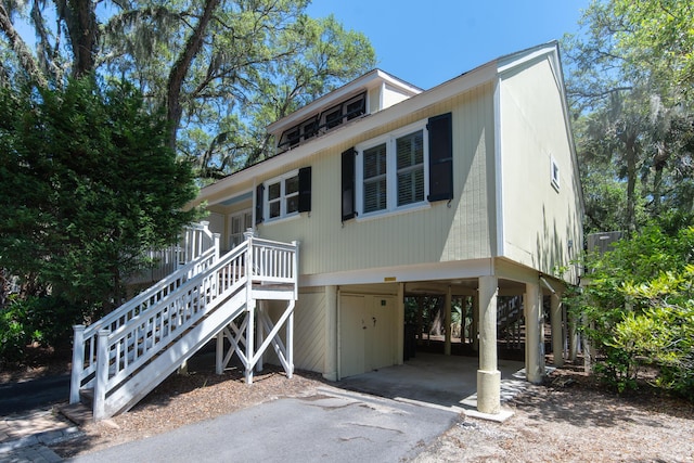 coastal inspired home with a carport, asphalt driveway, and stairs