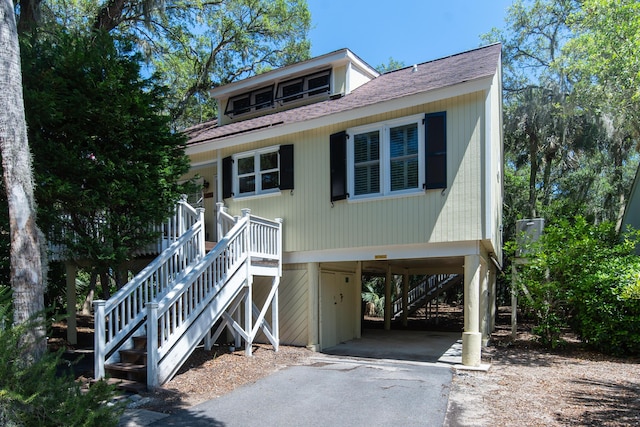 view of front facade featuring a carport, stairway, asphalt driveway, and roof with shingles