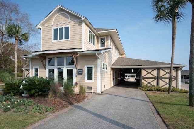 view of front of home featuring driveway, a carport, and roof with shingles