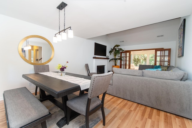 dining room with light wood-style floors, a fireplace, and a chandelier