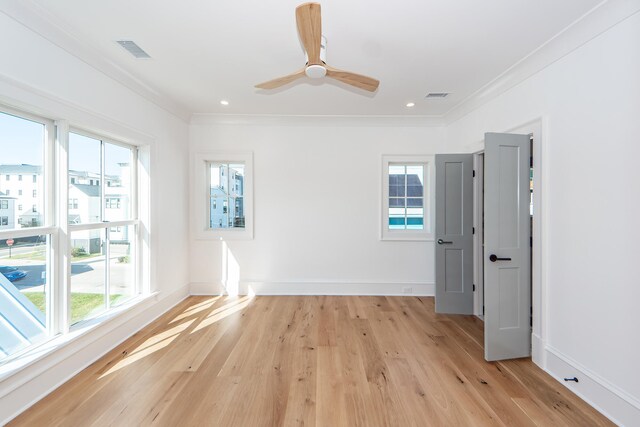 spare room featuring ornamental molding, a healthy amount of sunlight, and light hardwood / wood-style floors