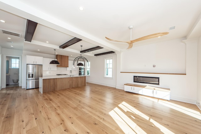 kitchen featuring white cabinets, stainless steel fridge with ice dispenser, light hardwood / wood-style flooring, and a large island