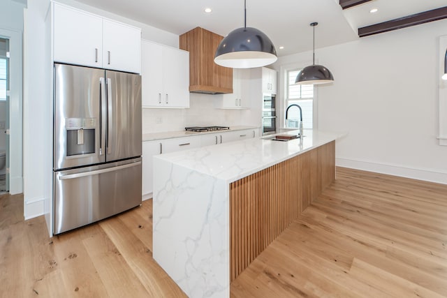 kitchen with white cabinetry, hanging light fixtures, light hardwood / wood-style floors, a center island with sink, and appliances with stainless steel finishes