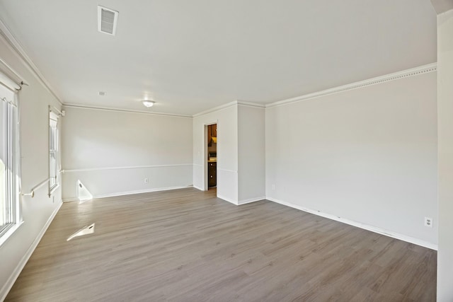 spare room with ornamental molding and light wood-type flooring