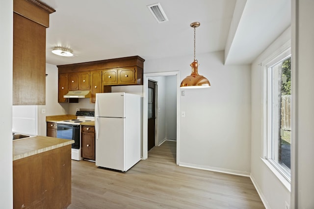 kitchen featuring white appliances, decorative light fixtures, and light hardwood / wood-style floors