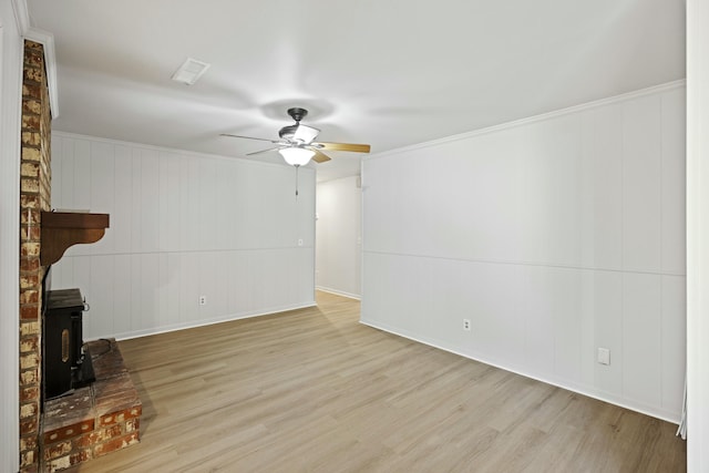 unfurnished living room with a wood stove, ceiling fan, and light hardwood / wood-style flooring