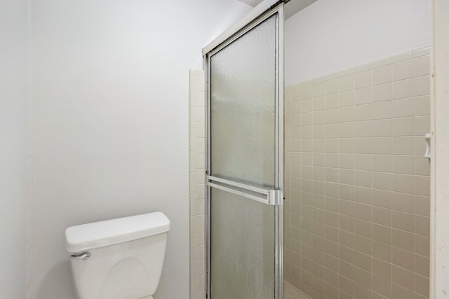 bathroom featuring toilet and an enclosed shower