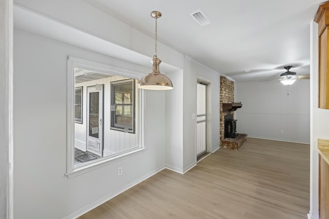 interior space with a brick fireplace, light hardwood / wood-style flooring, and ceiling fan