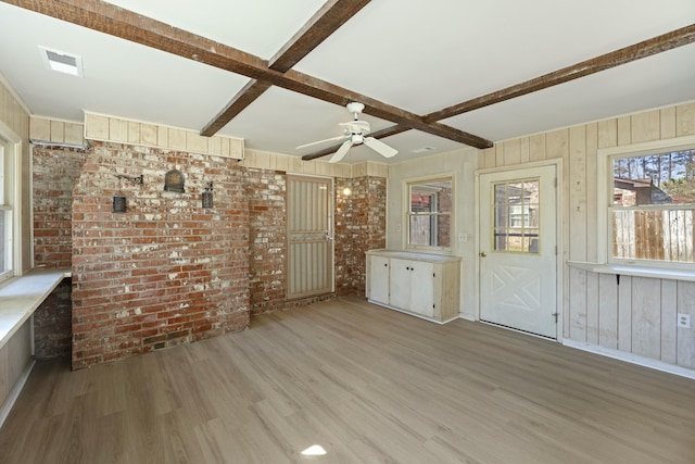 interior space with wooden walls, brick wall, beam ceiling, and light wood-type flooring