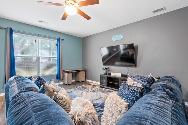 living area with visible vents, a ceiling fan, baseboards, and wood finished floors