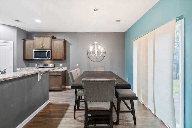 dining room with visible vents, light wood-style flooring, and an inviting chandelier