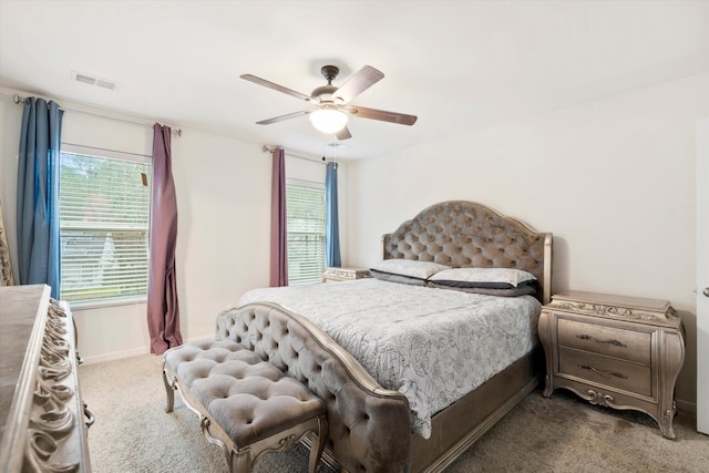 carpeted bedroom with visible vents, baseboards, and a ceiling fan