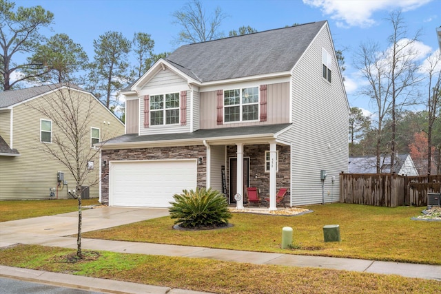 traditional-style home with stone siding, fence, concrete driveway, an attached garage, and a front yard