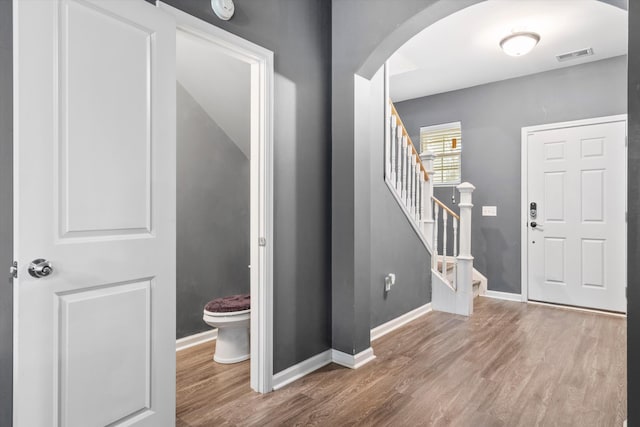 entrance foyer with visible vents, wood finished floors, stairway, arched walkways, and baseboards