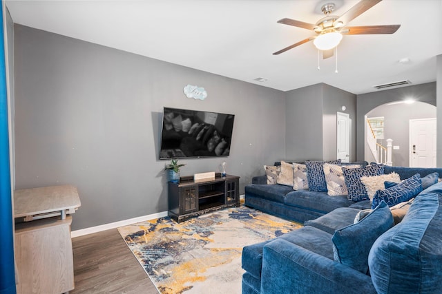 living area featuring visible vents, a ceiling fan, wood finished floors, arched walkways, and baseboards