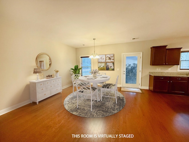 dining space with dark wood-style floors, a chandelier, visible vents, and baseboards