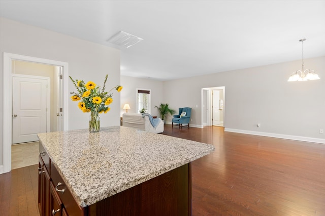 kitchen featuring hanging light fixtures, light stone countertops, and dark wood finished floors